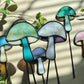 Colorful mushroom-shaped glass on sticks held by a hand with a light background